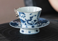Blue and white porcelain butterfly handle coffee cup on dark wood surface