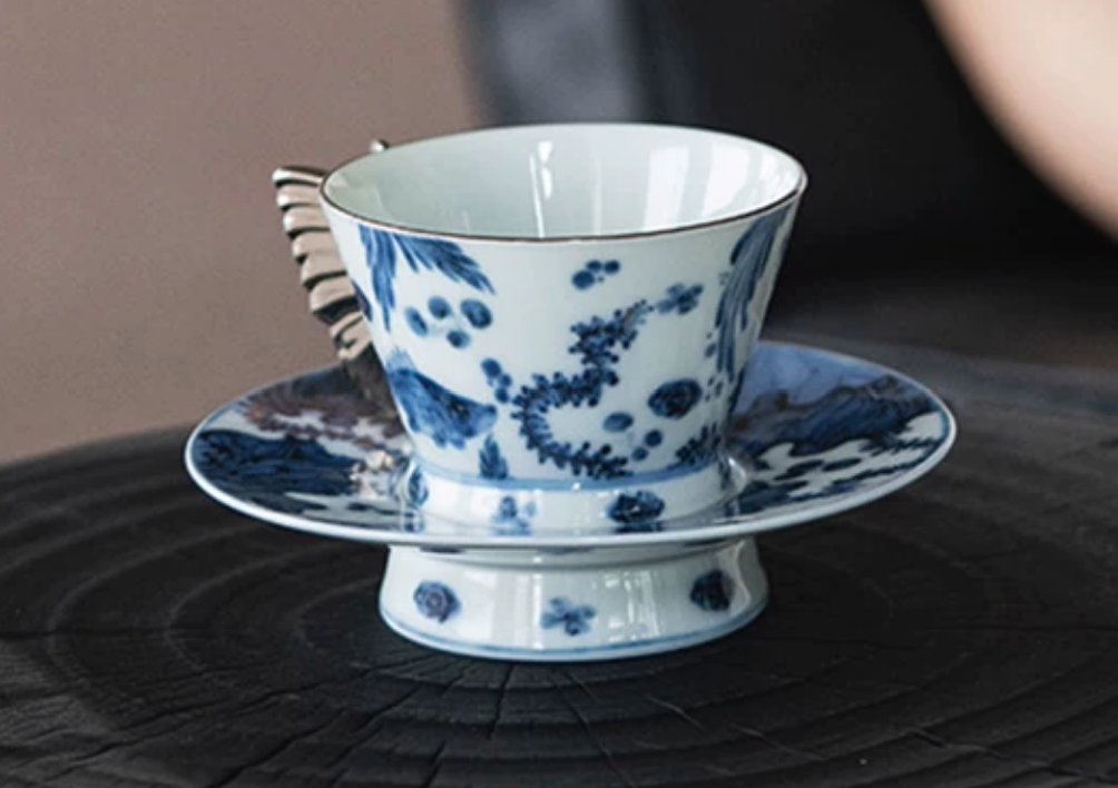 Blue and white porcelain butterfly handle coffee cup on dark wood surface
