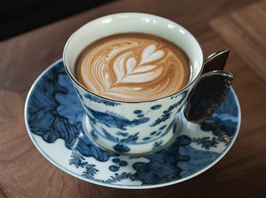 Latte art in blue and white porcelain butterfly coffee cup on wooden table
