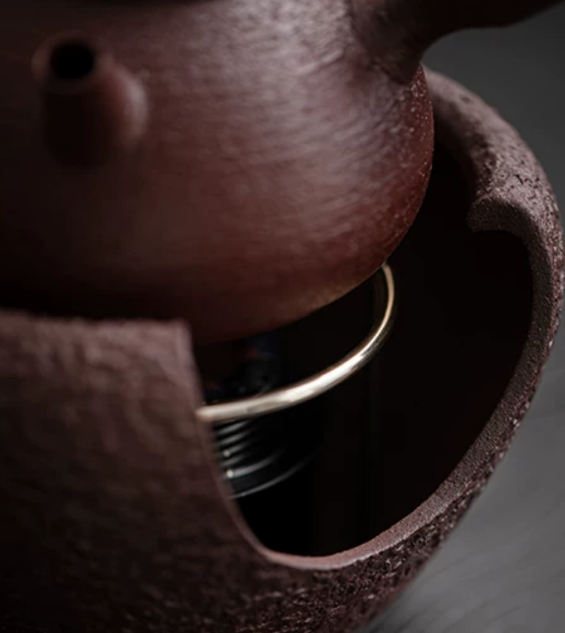 Steaming coarse pottery kettle on stove base