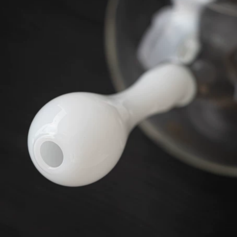 Pouring hot tea from glass side-handle kettle