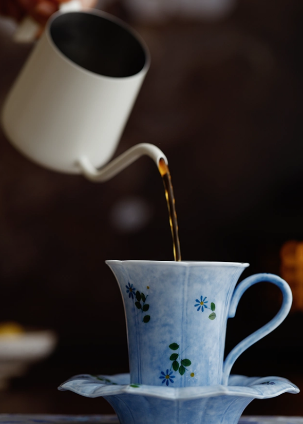Tea being poured into hand-painted blue floral porcelain cup